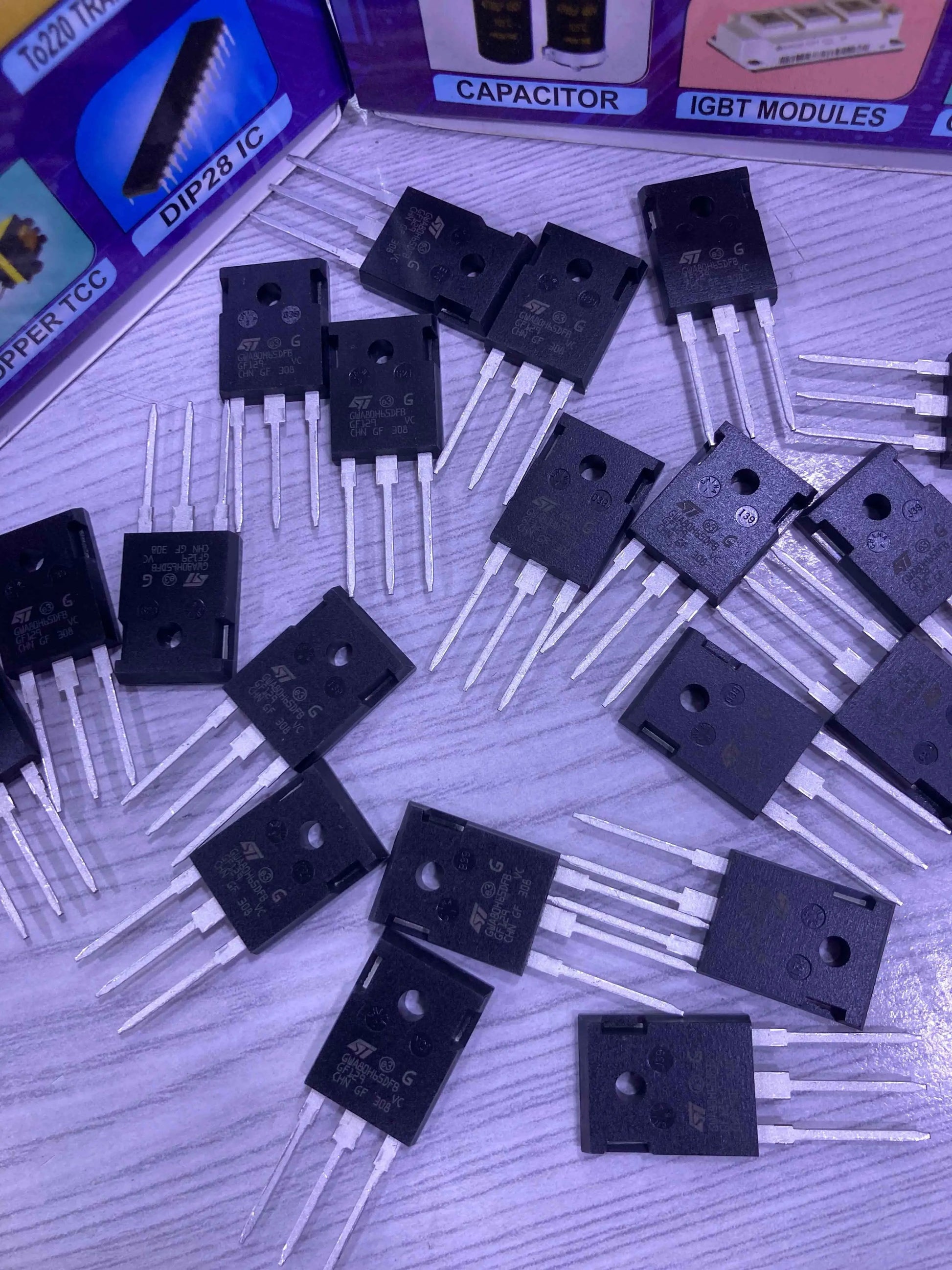 Collection of 80H65 650V 120A High Speed Trench Gate IGBT Scattered On A Wooden Surface