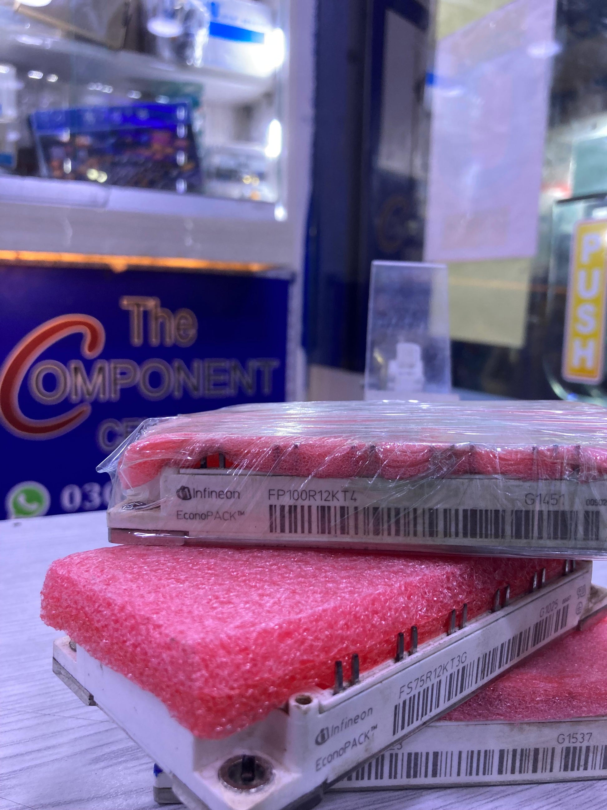 Infineon FP100R12KT4 power module with pink protective foam on white surface at The Component Centre