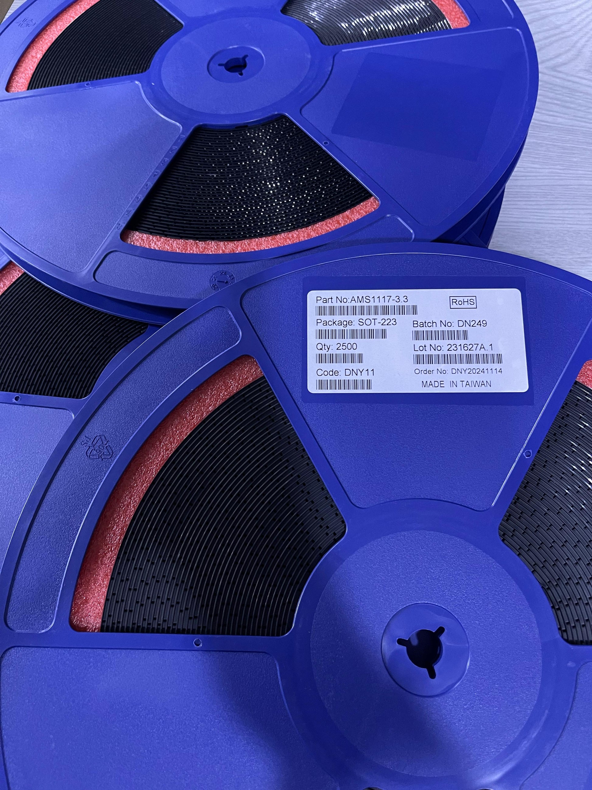 Blue reels of electronic components labeled AMS11173.3V from The Component Centre with packaging details visible