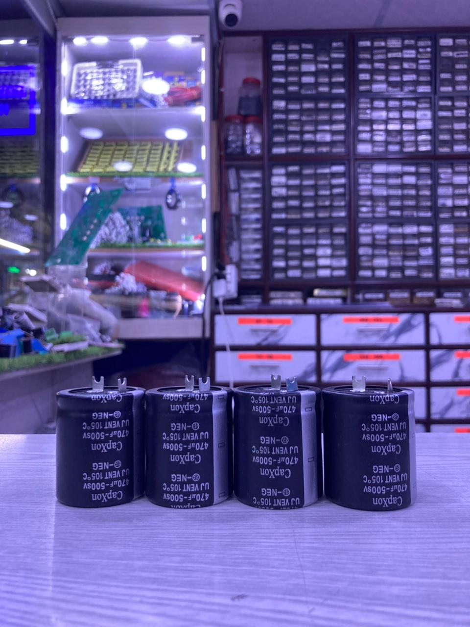 Four black electrolytic capacitors 820uF 450V on counter in electronics parts shop The Component Centre