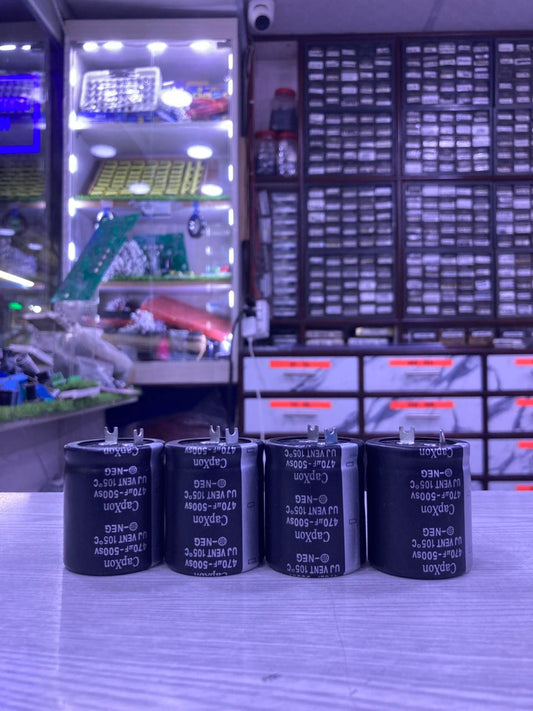 Four black electrolytic capacitors 820uF 450V on counter in electronics parts shop The Component Centre