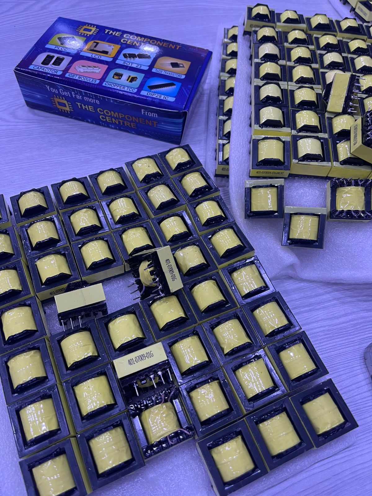 Bulk yellow PCB mounted inductors in black trays with The Component Centre box 401-070004-00G