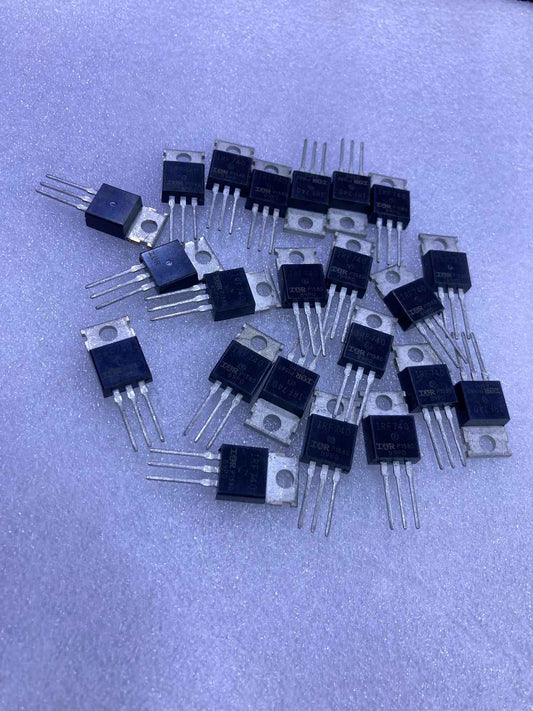 Multiple IRF740 electronic transistors with three pins and metal tabs on a soft surface