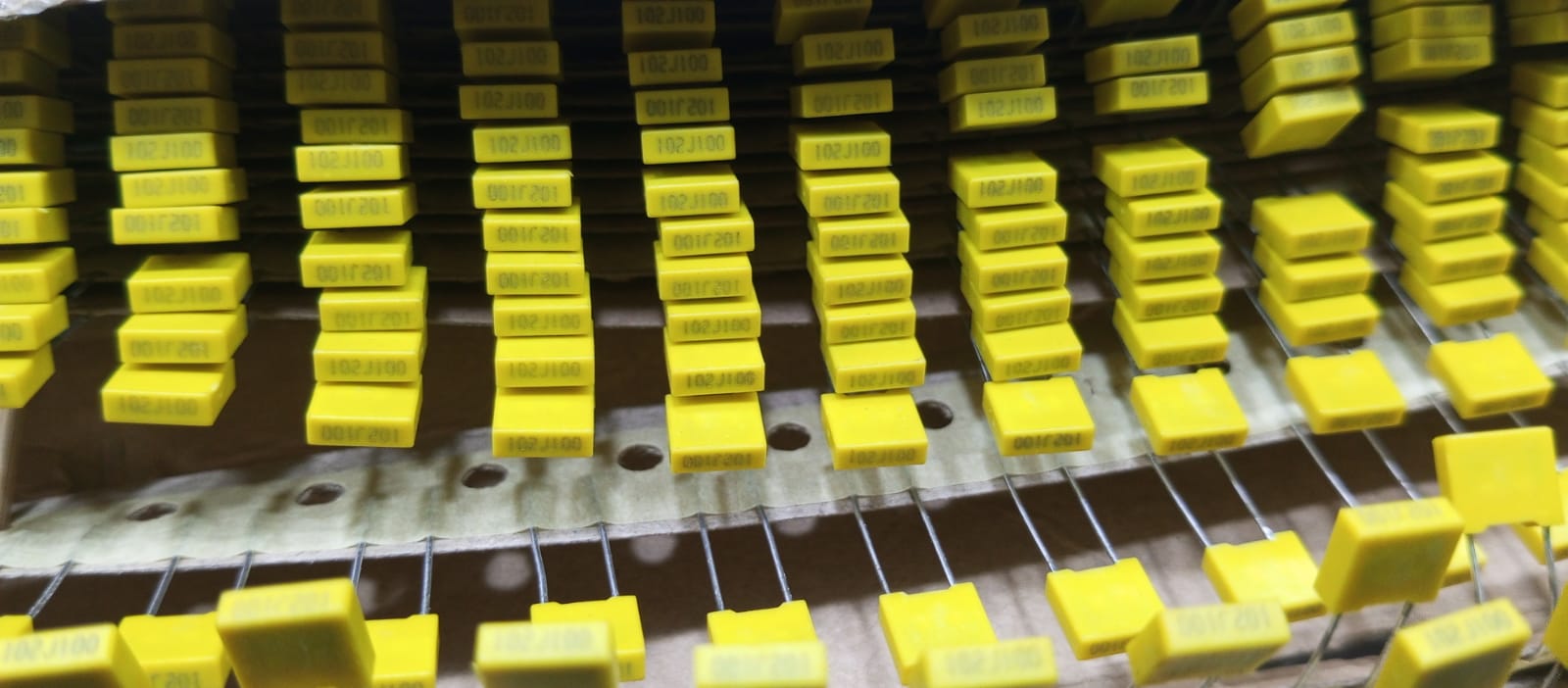 Rows of yellow 104J100 0.1uF capacitors neatly arranged on display at The Component Centre