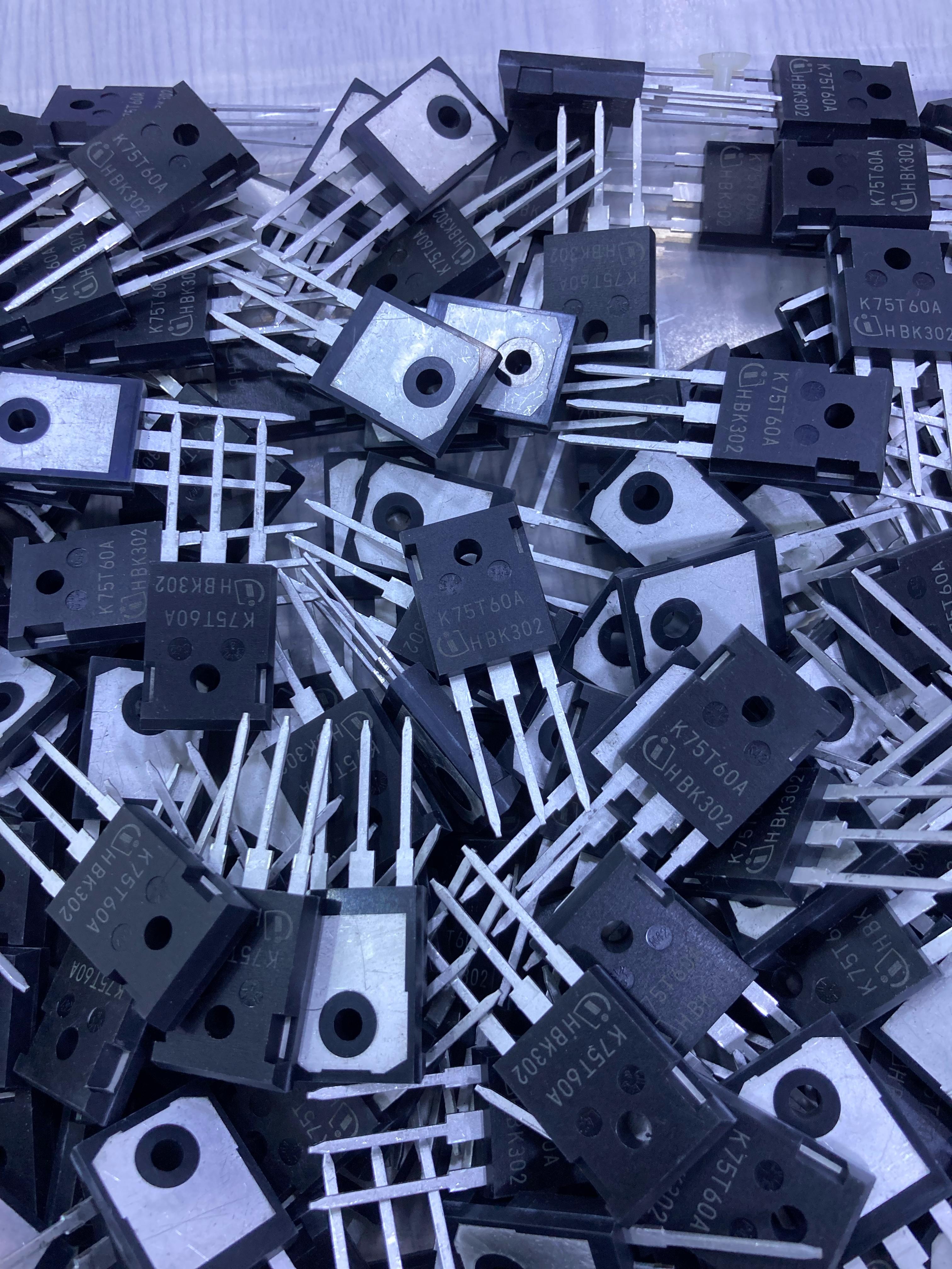 Pile of black K75T60 semiconductor transistors with three metal legs from The Component Centre