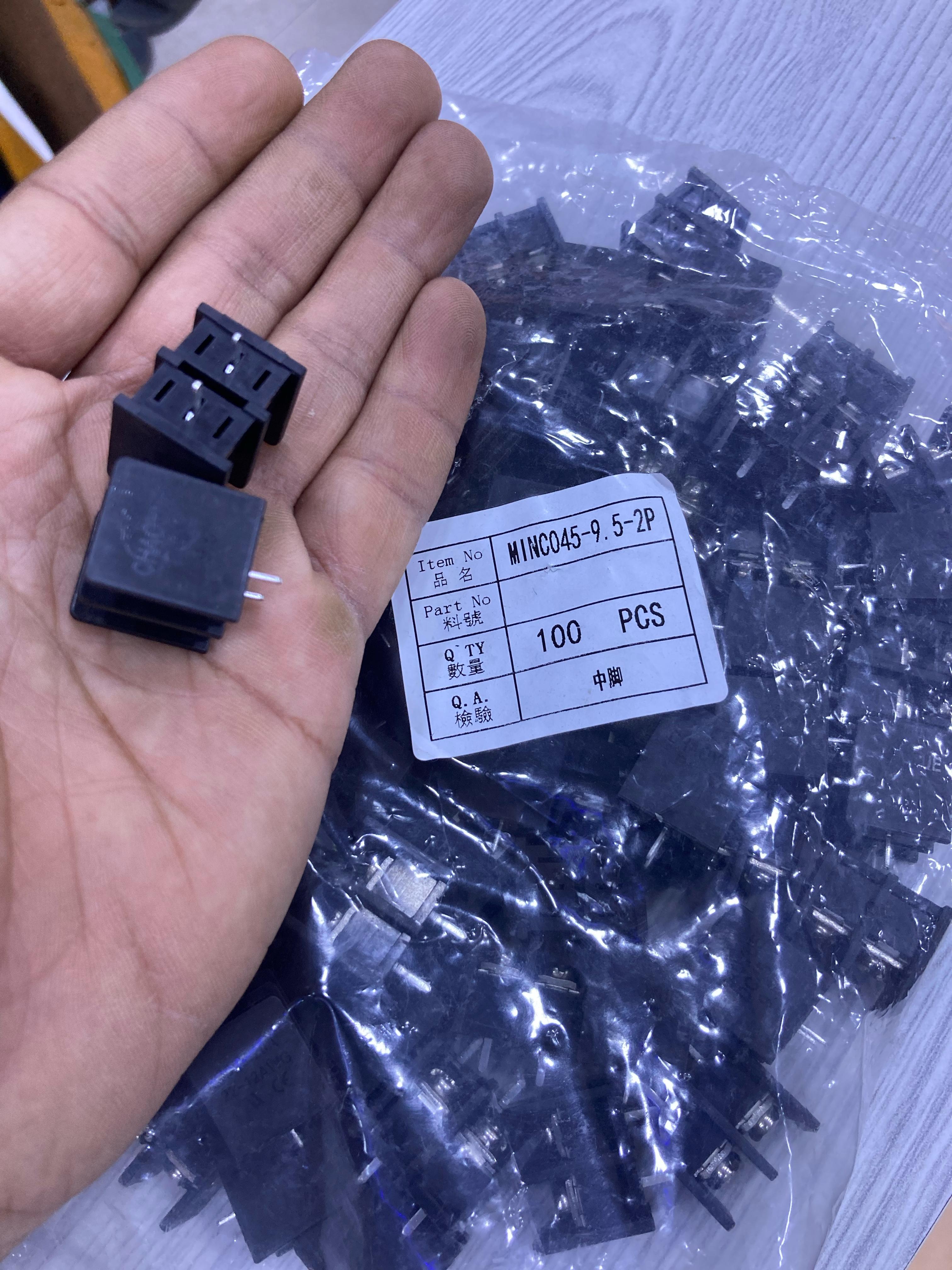 Hand holding KF45 electronic connectors with a bag of 100 black KF45 components from The Component Centre