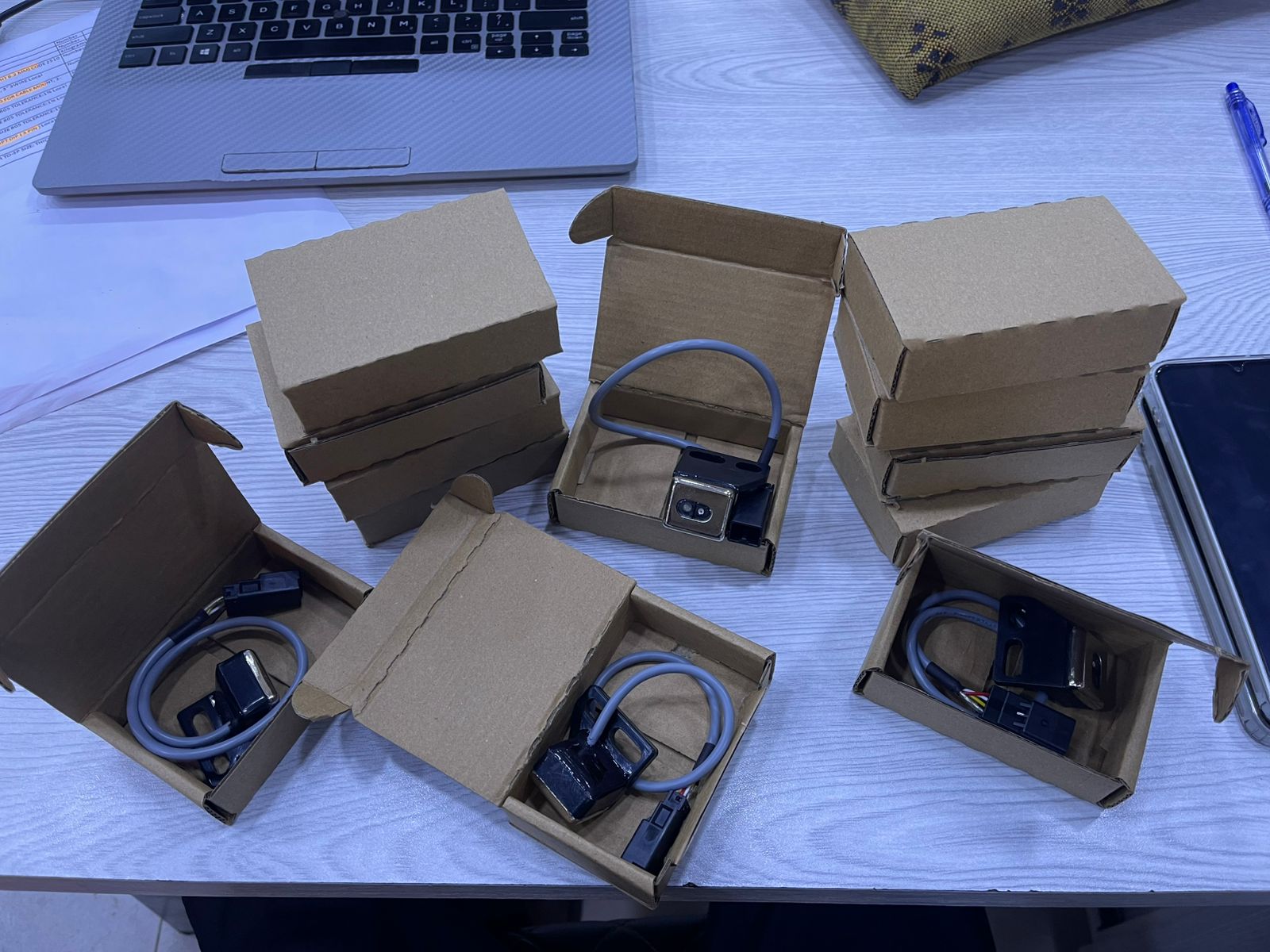 Leno sensor Toyota 710 units packed in small cardboard boxes on a desk with laptop and tablet nearby