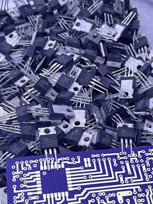 Pile of black NCEP85T16 electronic components with metal pins and a blue circuit board
