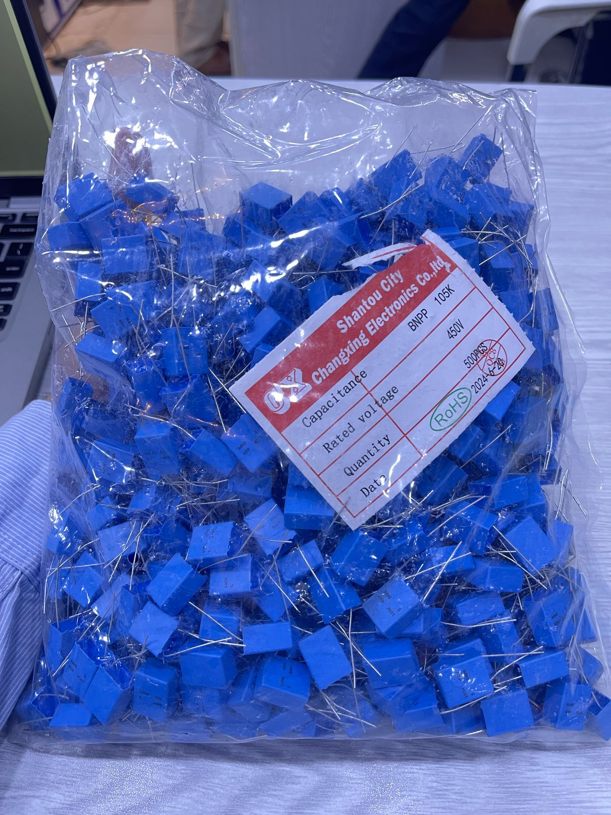 Bag of blue 105J 630V capacitors from The Component Centre with metal leads for electronic circuits