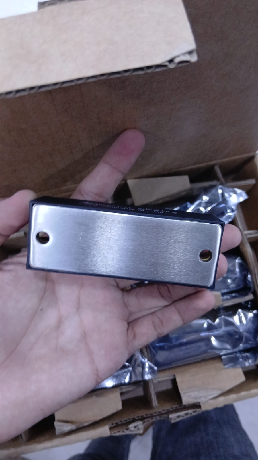 MDC200-16 metal component displayed held in hand with a box of similar items in the background