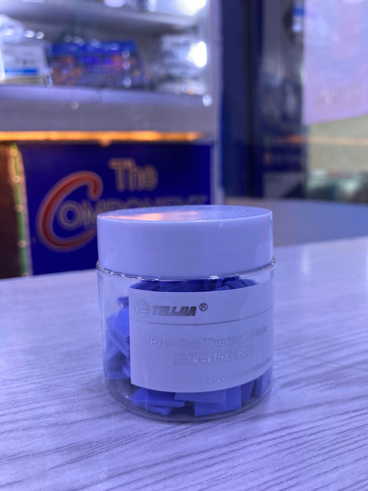 Jar of blue Pre-Cut Thermal Silicone Pads in clear plastic container with white lid on counter