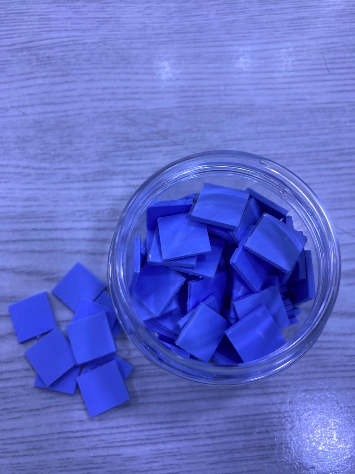Jar of blue square Pre-Cut Thermal Silicone Pads in a clear jar on wood surface for electronics cooling
